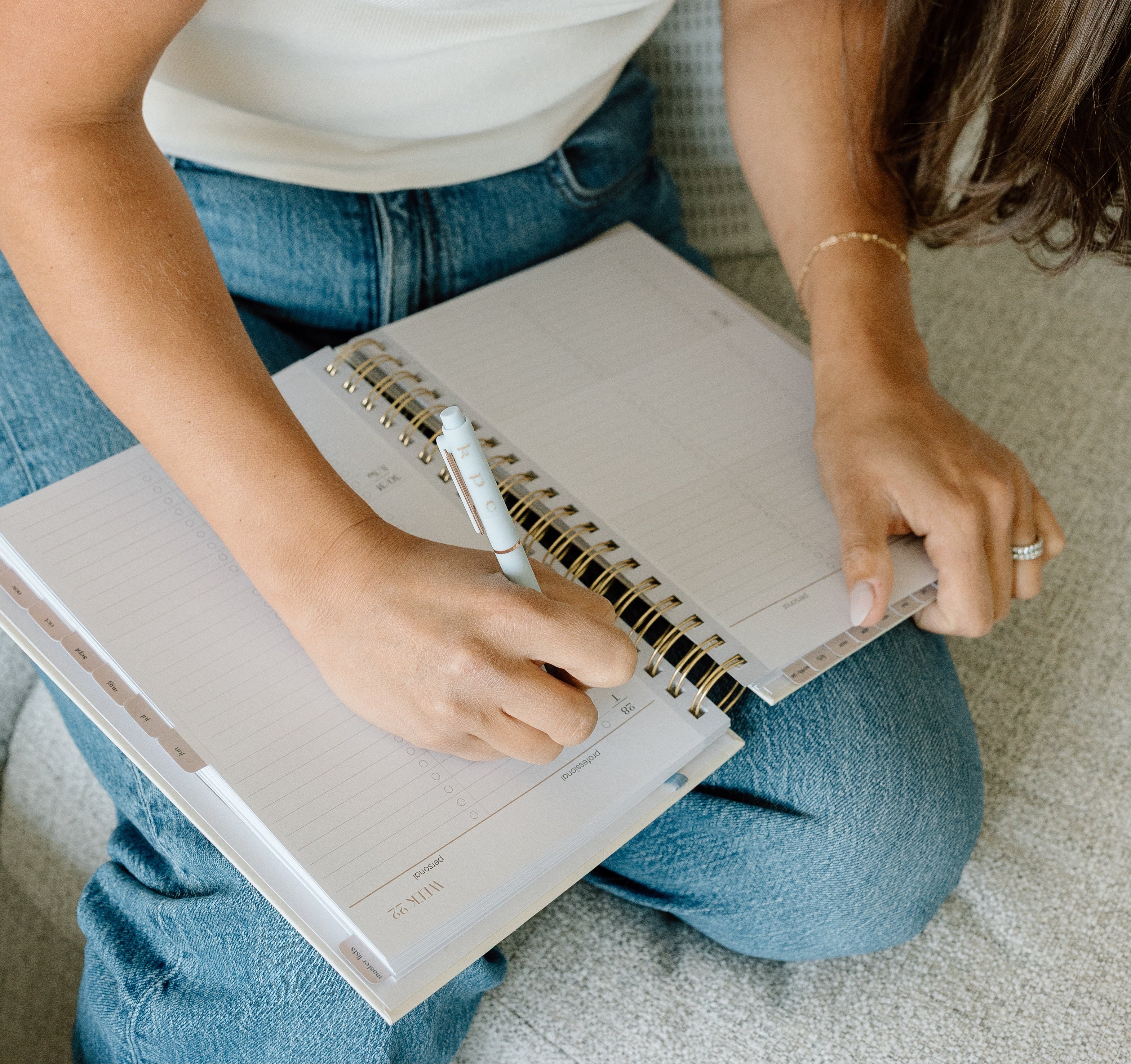 Woman writing in a notebook with a pen on a light-colored surface